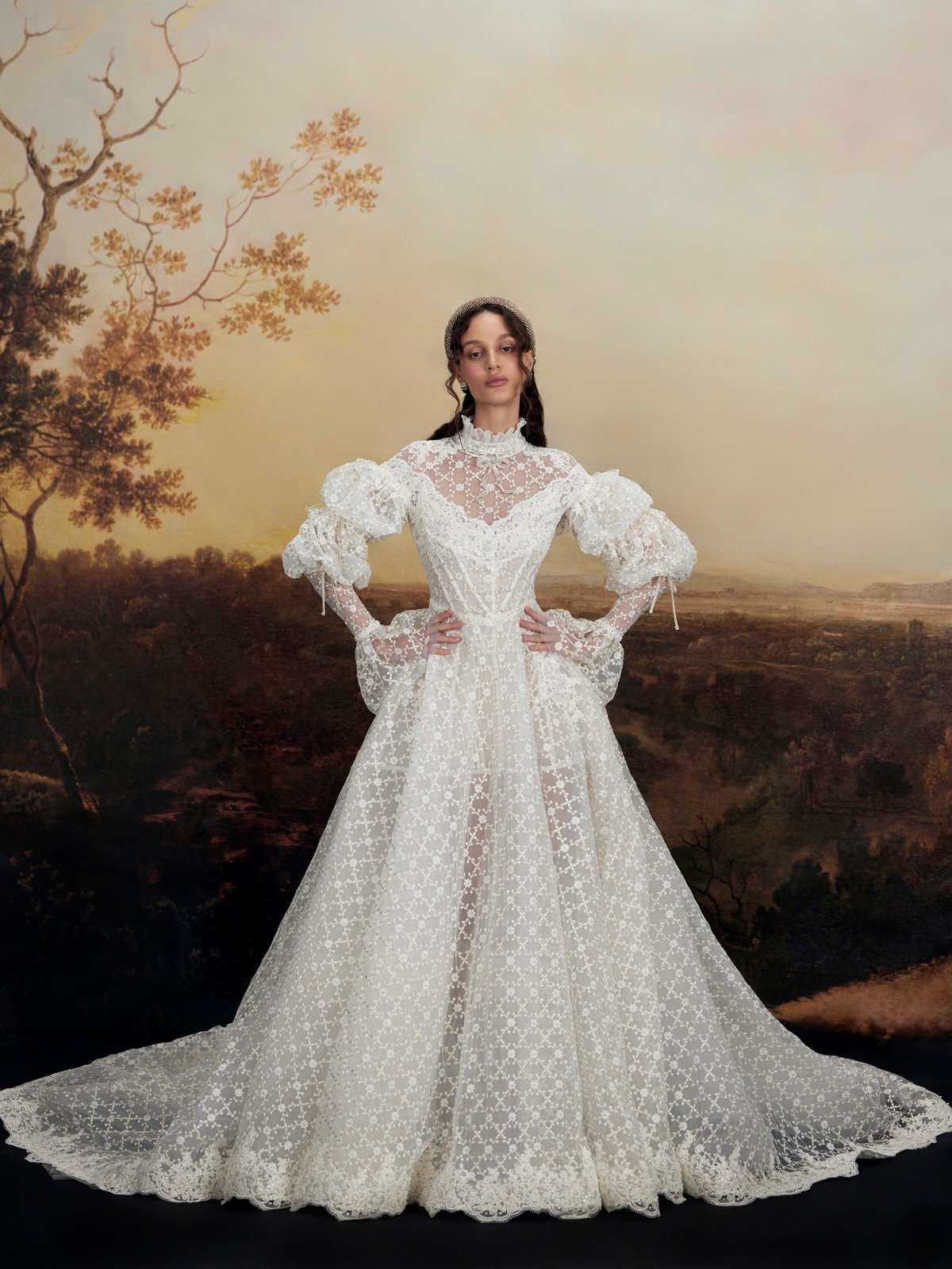 Bride in an ornate lace gown against a painted landscape backdrop